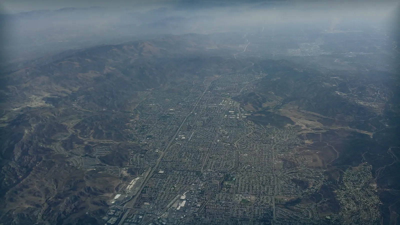 Vista aérea de un valle urbanizado entre montañas, el tipo de zona donde se contratan estudios de deformación del terreno.